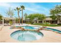 A backyard pool featuring rock accents, palm trees, a lounge area and integrated jacuzzi at 10726 Hawes End Ct, Las Vegas, NV 89183