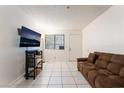 Living room with tile flooring, large TV, comfortable couch and window views at 1361 E University Ave # 106, Las Vegas, NV 89119
