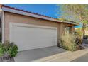 Close up of an attached two-car garage with a concrete driveway and small bushes in front at 2852 Red Ct, Las Vegas, NV 89123