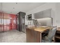 Compact kitchen features stainless steel appliances, modern lighting and a breakfast bar with chairs at 4381 W Flamingo Rd # 27308, Las Vegas, NV 89103