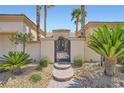 Close up of front gate, with stone pathway leading to a decorative wrought iron gate surrounded by lush desert landscaping at 4564 Bersaglio St, Las Vegas, NV 89135