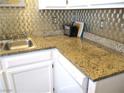 Close up of granite countertop with a stainless steel sink and white appliances in a stylish kitchen at 6480 Annie Oakley Dr # 111, Las Vegas, NV 89120