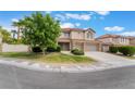 View of a two-story home with a red tile roof, three car garage, and landscaped front yard at 7632 Spruce Run Ct, Las Vegas, NV 89128
