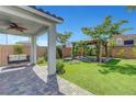 Well-manicured backyard with a covered patio, a swing bench, verdant lawn, and lush landscaping at 8349 Pollenzo Ave, Las Vegas, NV 89178