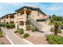 Exterior of a tan two-story condo with desert landscaping,stairs to the entrance, and a view of the sky at 8410 Eldora Ave # 2082, Las Vegas, NV 89117