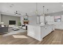 Open-concept living room and kitchen with hardwood floors, fireplace, ceiling fans, and a large center island at 2805 Proust Ct, Henderson, NV 89044
