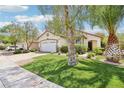 Curb view of a single-story house showing a large lawn, mature landscaping, and an attached two-car garage at 3029 Paseo Hills Way, Henderson, NV 89052