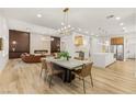 Open-concept dining room features modern chandelier, table with seating, and wood-look tile floors at 800 Jody Brook Ct, Las Vegas, NV 89145