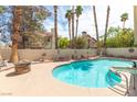 Relaxing backyard oasis featuring a sparkling pool with a spa, mature trees and privacy wall at 94 Fantasia Ln, Henderson, NV 89074