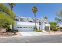 View of the front exterior featuring a three car garage and desert landscaping with mature trees at 2209 Purple Majesty Ct, Las Vegas, NV 89117