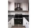 A kitchen featuring stainless steel range hood and oven against white cabinets and black hardware at 3275 Arville St # C, Las Vegas, NV 89102