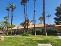 Manicured lawn and mature trees highlighting community building under blue sky at 5220 Mission Carmel Ln # 101, Las Vegas, NV 89107