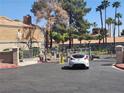 Gated entrance to a residential area with tiled-roof buildings and a white car driving through at 5220 Mission Carmel Ln # 101, Las Vegas, NV 89107