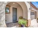 Inviting entryway with a stucco archway, decorative plants, and a stylish gray front door at 10976 Bluebell Basin Rd, Las Vegas, NV 89179