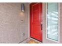 A striking red front door is complemented by a contemporary exterior light fixture at 11228 Burning River St, Las Vegas, NV 89183