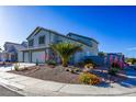 Charming two-story home with a two-car garage and desert landscaping, including a palm tree and colorful flowering shrubs at 7800 Four Seasons Dr, Las Vegas, NV 89129