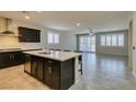 Modern open kitchen with a large island, dark cabinetry, and stainless steel appliances at 1128 Via Della Curia, Henderson, NV 89011