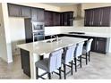 Modern kitchen featuring a large island, stainless steel appliances, and dark cabinetry at 1128 Via Della Curia, Henderson, NV 89011