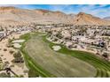Aerial view displays rolling green fairways and sand traps of the golf course surrounded by mountains and luxury homes at 11534 Glowing Sunset Ln, Las Vegas, NV 89135