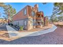 Lovely two-story condo with stucco exterior, terracotta roof, and charming balcony, surrounded by mature landscaping and walkway at 211 Mission Laguna Ln # 205, Las Vegas, NV 89107