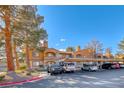 Attractive condo complex featuring stucco exteriors, terracotta roofs, balconies, covered parking, and mature shade trees at 211 Mission Laguna Ln # 205, Las Vegas, NV 89107