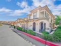 Stylish townhouse with arched entryway, lush landscaping, and a community street view at 24 Via Vasari # 104, Henderson, NV 89011