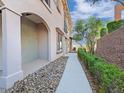 Townhouse exterior featuring a paved walkway, stone landscaping, and arched architectural details at 24 Via Vasari # 104, Henderson, NV 89011