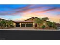 Charming single-story home boasts a three-car garage and lush landscaping under a vibrant sunset sky at 3870 Valles Caldera Ct, Las Vegas, NV 89118