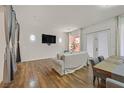 Cozy living room featuring hardwood floors, a modern sofa, and large windows providing ample light at 4432 Vicobello Ave, Las Vegas, NV 89141