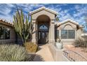 Beautiful home entry featuring an arched doorway, mature landscaping, and decorative features at 6308 Canyon Ridge Dr, Las Vegas, NV 89108