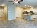 Open concept living room and kitchen with granite island, stainless steel appliances, and tile flooring at 7892 W Shelbourne Ave, Las Vegas, NV 89113