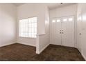 Bright foyer with neutral walls and carpet, featuring a window for natural light and a double-door entry at 9044 Crimson Clover Way, Las Vegas, NV 89134