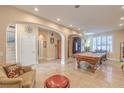 Spacious living area with travertine tile, showcasing archways, a staircase and a billiard table at 664 Blue Crystal Creek Rd, Henderson, NV 89002