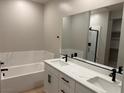Elegant bathroom featuring dual sinks, a soaking tub with marble surround, and modern fixtures at 3240 Walker River St, North Las Vegas, NV 89032