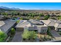 An elevated view of a modern home with paver driveway, desert landscaping, and mountain views at 10004 Terrastone Dr, Las Vegas, NV 89148