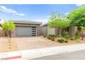 Modern home exterior boasts a stylish garage, stone detailing, neat landscaping, and a welcoming driveway at 103 Reflection Cove Dr, Henderson, NV 89011