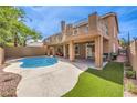 Inviting backyard featuring a sparkling pool, covered patio, balcony, artificial grass and a privacy fence, perfect for outdoor relaxation at 1112 Caraway Ln, Las Vegas, NV 89144