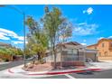 Corner lot home featuring desert landscaping, covered porch, and a community gate in the background at 173 Calm Morning Ave, Henderson, NV 89002