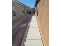Narrow side yard of a single story house, with gravel and a cemented path at 3425 Palatine Hills Ave, North Las Vegas, NV 89081