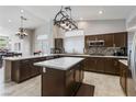 Modern kitchen with dark wood cabinets, a center island, stainless steel appliances, and tile backsplash at 7401 Bridlehorne Ave, Las Vegas, NV 89131