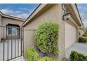 View of home's side entry gate and landscaping featuring desert landscaping and a two-car garage at 10241 Premia Pl, Las Vegas, NV 89135