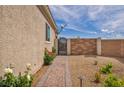 Gated side yard featuring desert landscaping with flower bushes and a patterned brick walkway at 1108 Via Della Curia, Henderson, NV 89011
