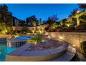 Beautifully landscaped backyard featuring a stone patio, lush greenery, and accent lighting for serene outdoor enjoyment at 12122 High Country Ln, Las Vegas, NV 89138