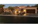 Exterior of a one-story home with beautiful landscaping, a paved driveway, and a two-car garage at dusk at 1725 Cypress Manor Dr, Henderson, NV 89012