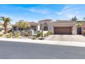 Street view of the single-story tan house with a two-car attached garage and mature landscaping at 1725 Cypress Manor Dr, Henderson, NV 89012