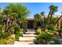 Lush landscaping complements the home's grand entrance, enhanced by palm trees and stone steps at 28 Painted Feather Way, Las Vegas, NV 89135