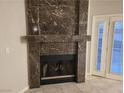 Close up of the living room's elegant marble fireplace with a black grate and a door to the backyard at 3621 Laguna Verde Way, Las Vegas, NV 89121