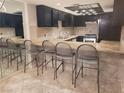 Modern kitchen with dark cabinetry, stainless steel appliances, and a breakfast bar with seating at 3621 Laguna Verde Way, Las Vegas, NV 89121