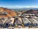 Stunning aerial view of houses in a desert community near mountains with a lake in the distance at 56 Tatahatso Point St, Henderson, NV 89011