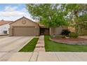 Inviting home with a well-kept lawn, stone pathway, mature landscaping, and a classic two-car garage at 619 Ancient Mayan Dr, Henderson, NV 89015